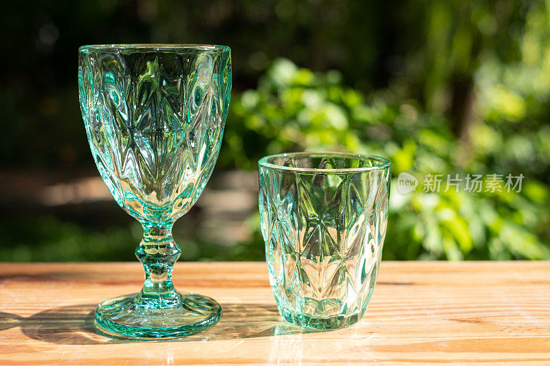 铀玻璃或蓝宝石水晶玻璃。青色玻璃器皿复古经典设计旧厨具在木桌户外阳光反射。