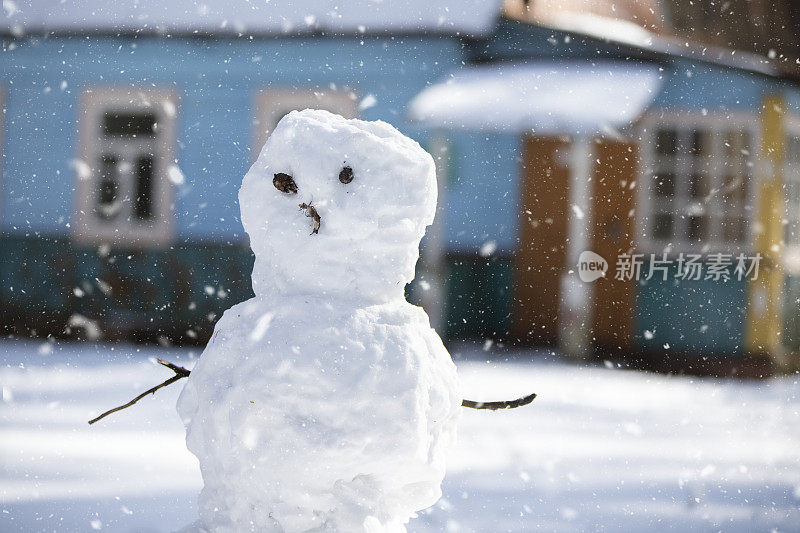 有趣的雪人，用树枝代替手臂和眼睛，背景是漫天飞舞的雪花。