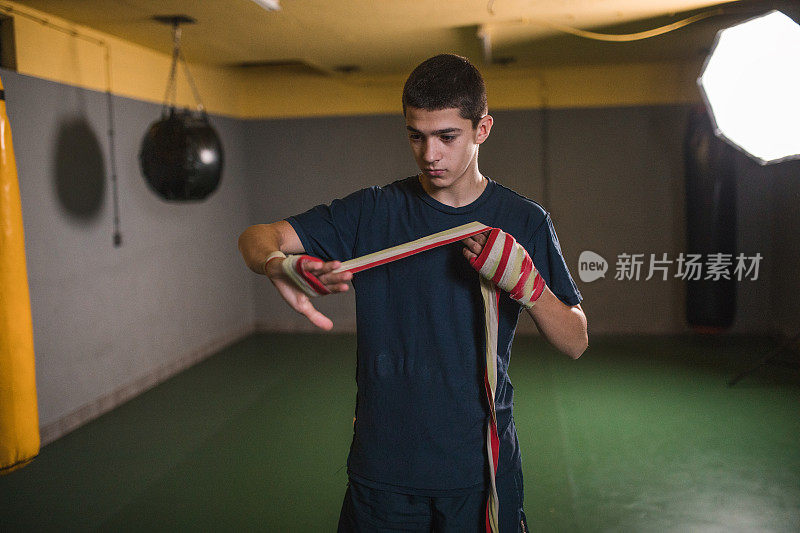 一个年轻的自由搏击运动员在戴上拳击手套之前用一块布包裹他的手，这有助于减少拳击对手时的冲击力，并有助于防止拳击受伤