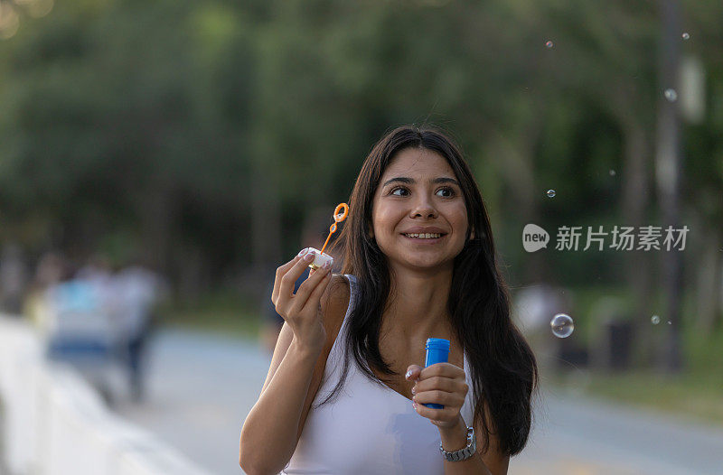 年轻女子正在外面吹泡泡。