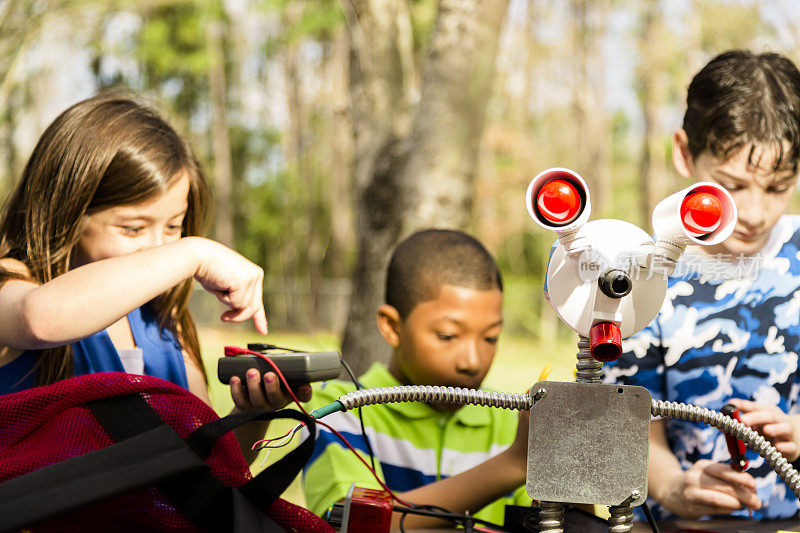 小工程师!民族小学的孩子们在他们创造的“机器人”上合作。