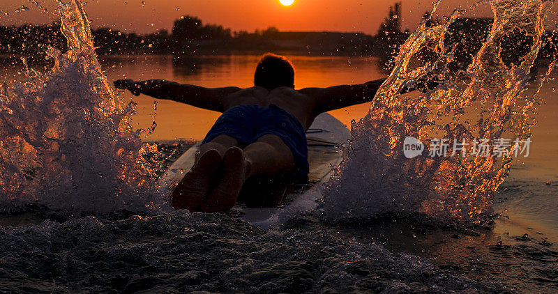 日落时分，一名男子在湖中划桨