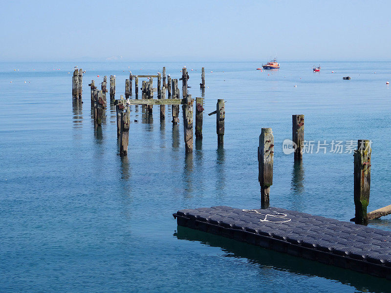 旧的腐烂的木制码头桩柱的形象，反映在海上