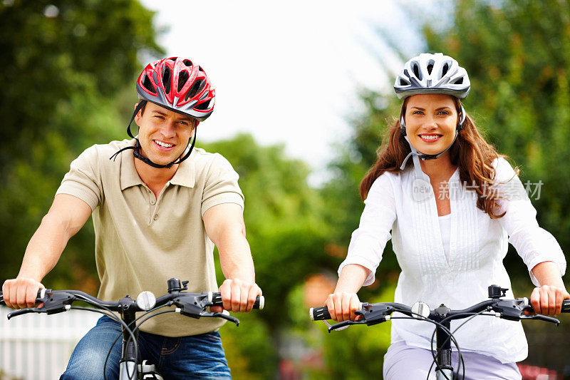 快乐的中年夫妇戴着头盔骑自行车