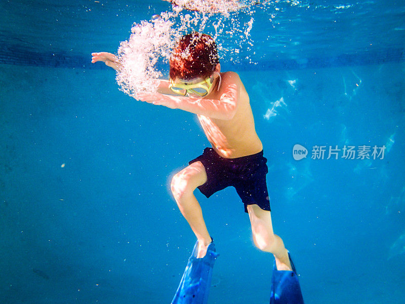 戴面具的小男孩在泳池里自由潜水