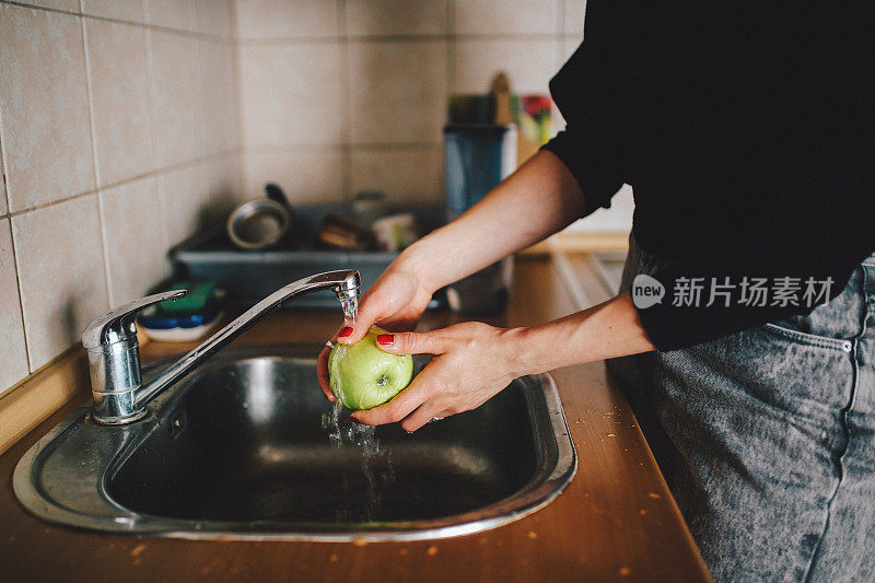 一个年轻女人在厨房里洗苹果