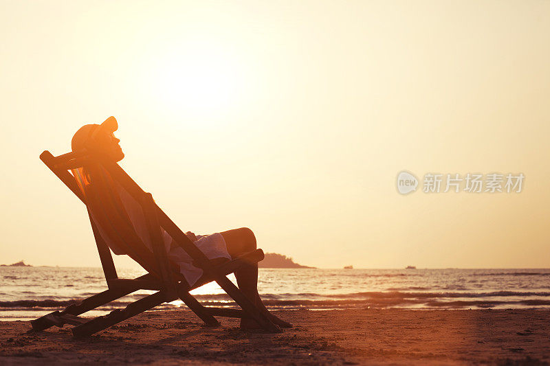 日落时分，女人在海滩上放松的剪影