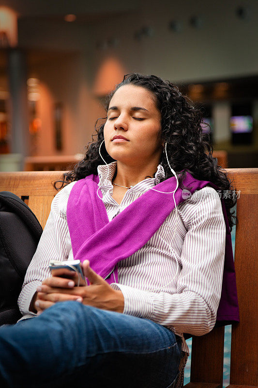 十几岁的女孩在机场候机时听音乐