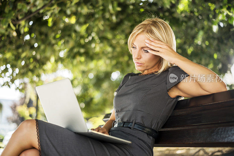 商务女性在户外使用笔记本电脑。