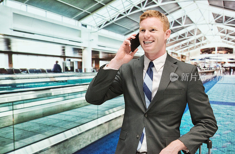 在机场用手机微笑的商人