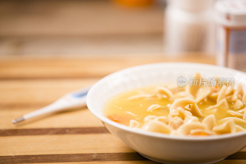 碗里的鸡汤面。药品、温度计。生病的食物。