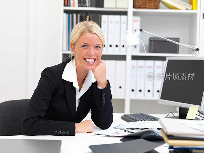 微笑的商务女性坐在办公桌前