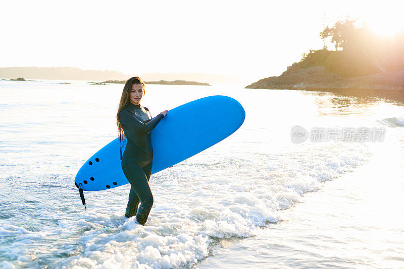 强壮美丽的年轻女人在海滩上冲浪