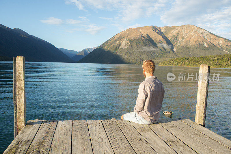 人坐在湖墩上，欣赏山湖风光