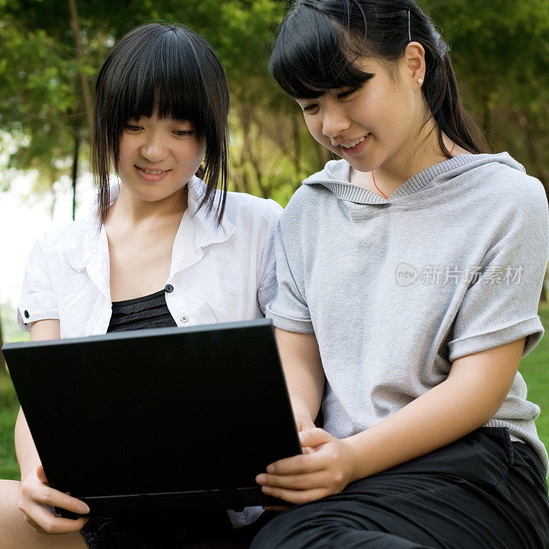 快乐的年轻亚洲女孩分享笔记本电脑