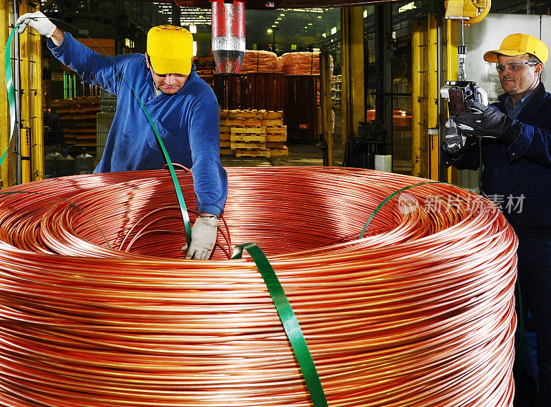 工人们用起重机将巨大的铜线卷堆叠起来