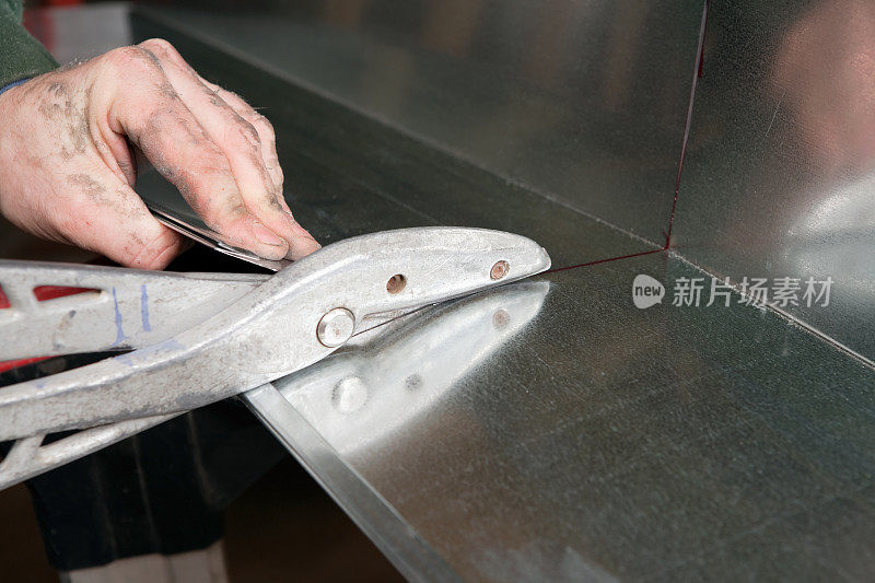 暖通空调安装人员使用锡剪修剪管道钣金