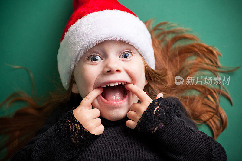 兴奋的女孩戴着圣诞老人的帽子和微笑