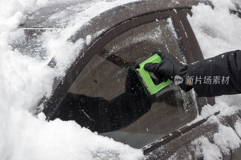 男人在一场雪后清理汽车