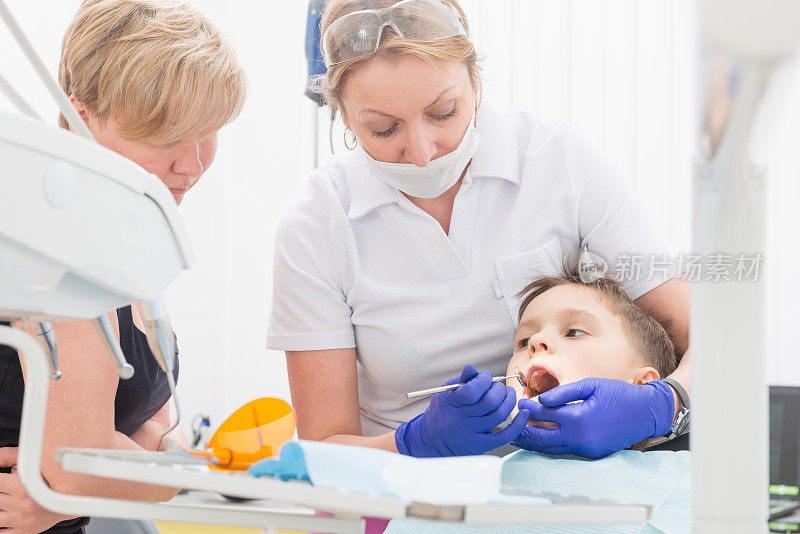 一个男孩和一个母亲正在给牙医治疗牙齿