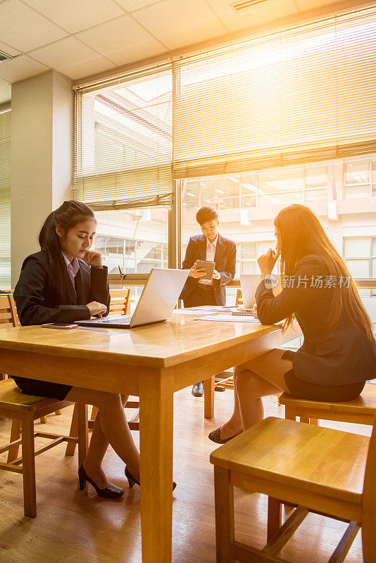 专业行政短黑发亚洲商务女性手执书本与女性同事工作，沟通科技银行理念。