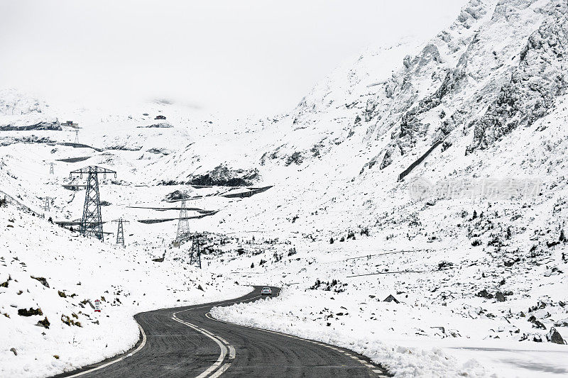 白色汽车在白雪皑皑的山脉上的发夹弯道上