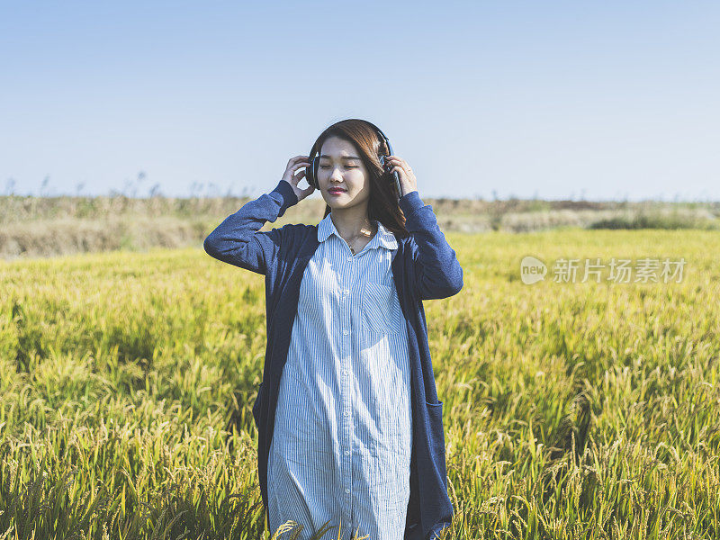 年轻女孩戴着耳机在野外