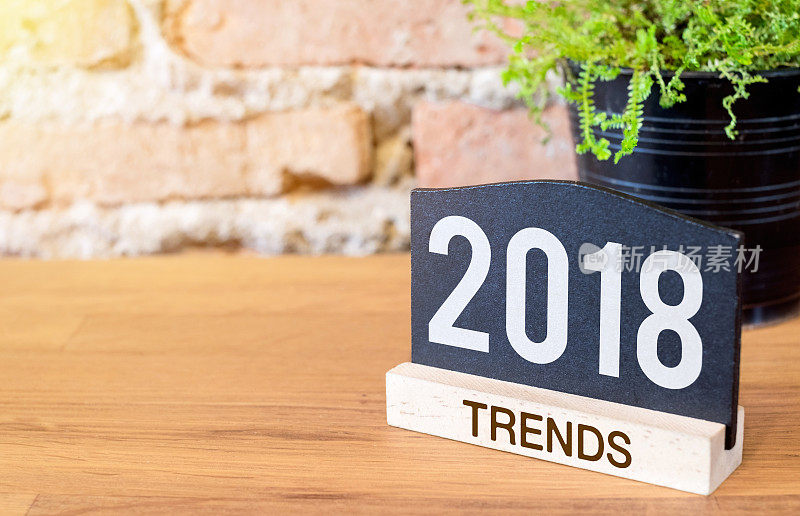 2018年新年趋势的黑板报和绿色植物的木桌在砖墙。明年的商业计划。