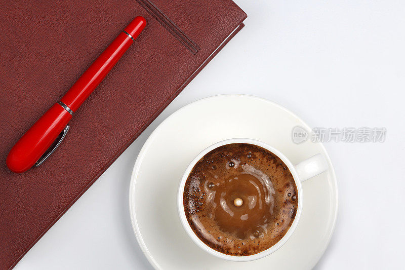 红笔在杯子上有黑咖啡和一个笔记本