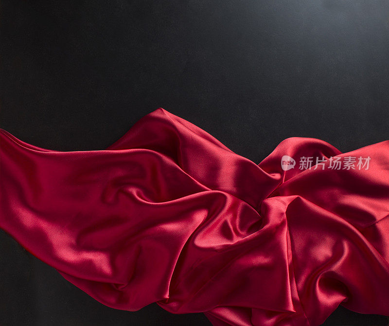 自由流动的红色缎子在黑色的背景。