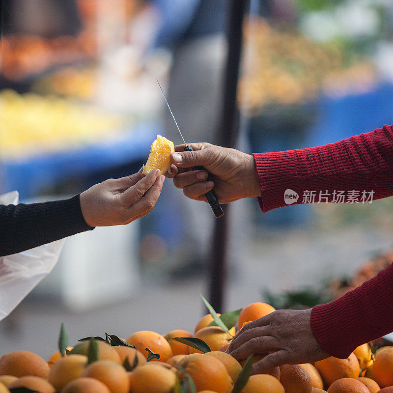 在农贸市场，卖家向买家提供橙子片
