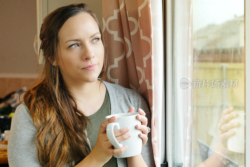 焦急的女人一边喝着咖啡一边望着窗外