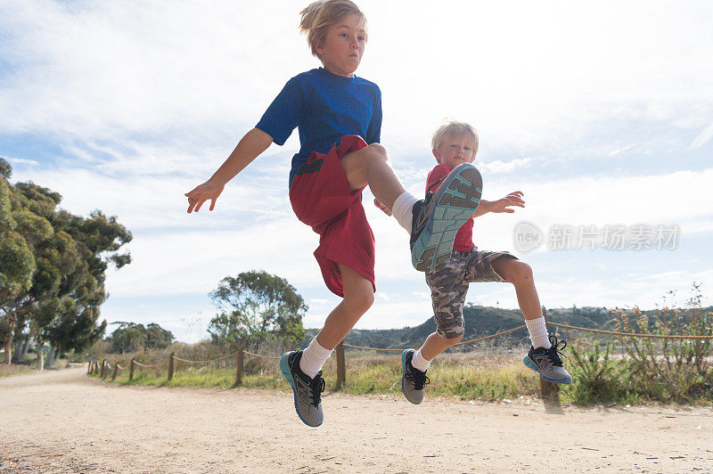 两个孩子在泥土路上沿着泻湖奔跑