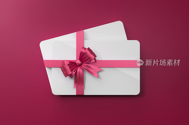 白色礼品卡与粉红色蝴蝶结在粉红色的背景