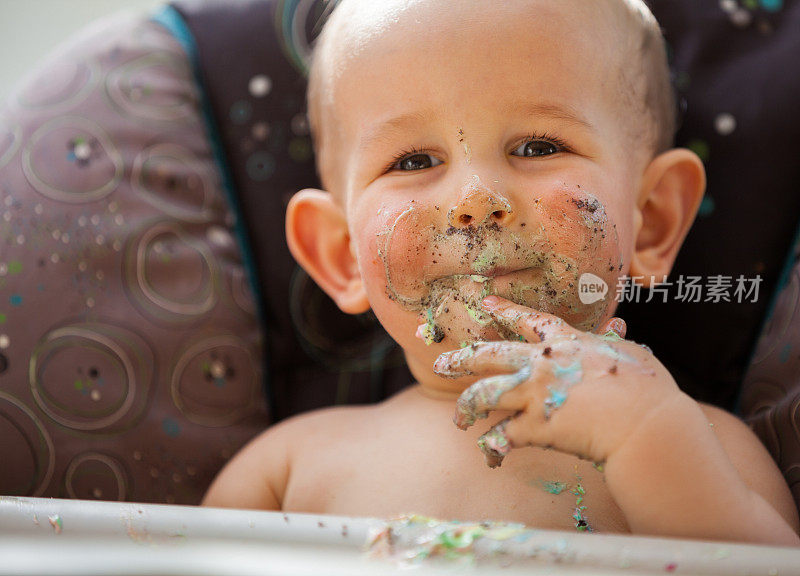 一个一岁的小男孩脸上挂着生日蛋糕