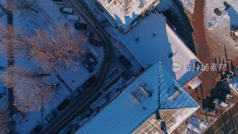 俯视图，正上方鸟瞰被雪覆盖的冬季城市住宅区。攀爬和旋转复杂的摄像机运动。