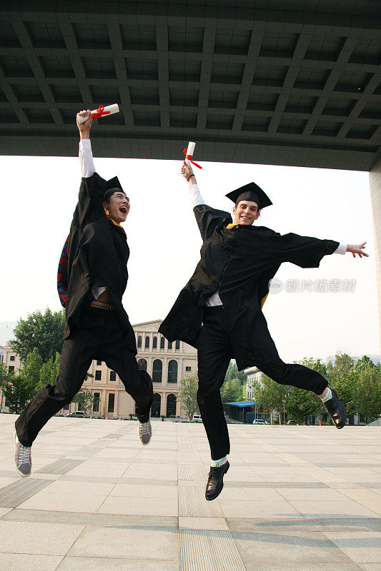 两个身穿学士服的大学生兴奋跳跃