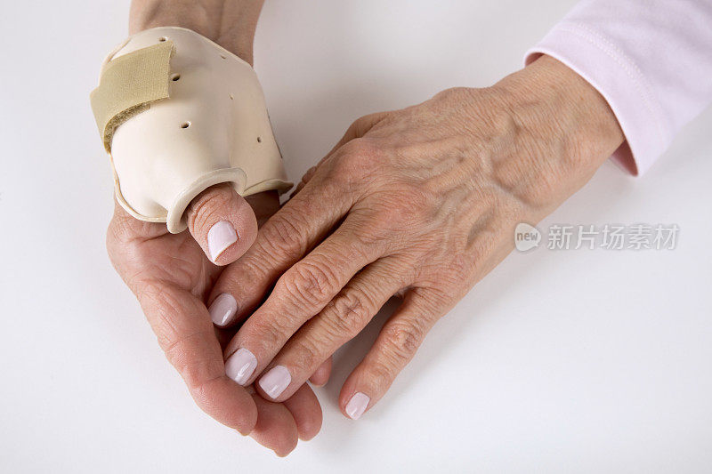 老年妇女戴着关节炎支架抚摸手