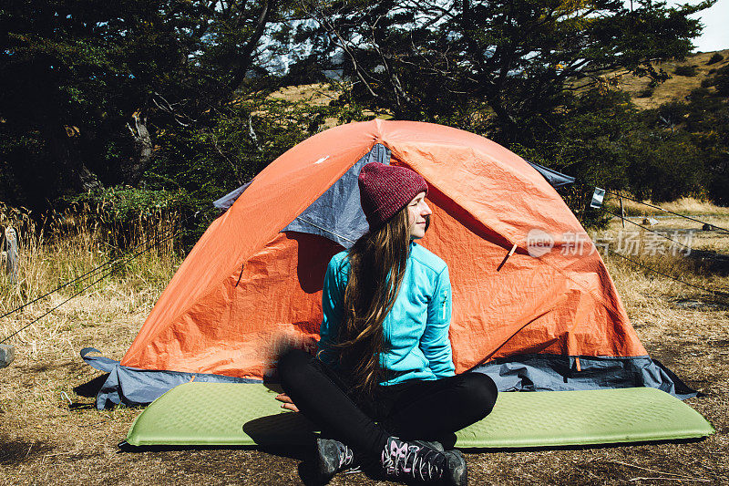 一名女子徒步旅行后在托雷斯德尔潘恩国家公园的帐篷附近休息
