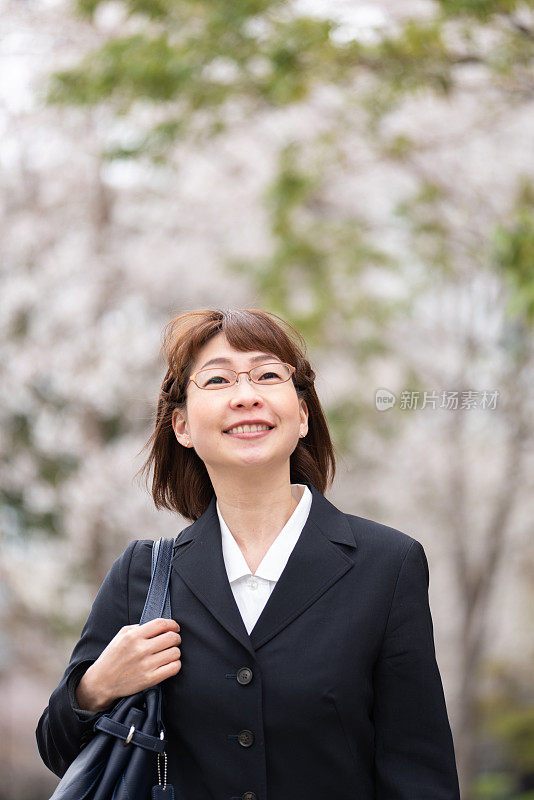 女商人走在樱花盛开的街上