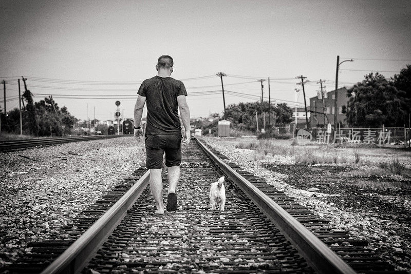 在铁轨上散步的人和他的狗