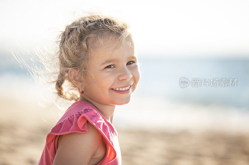 阳光明媚的海滩上，可爱的小女孩微笑着