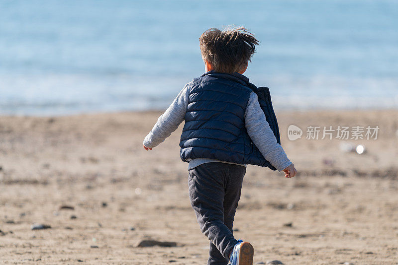 秋天，小男孩在海滩上跑步