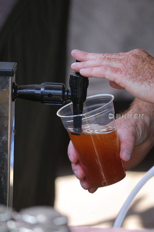 近距离看不出的酒保倒生啤酒在一次性饮用品脱玻璃杯，啤酒泵水龙头倒生啤酒