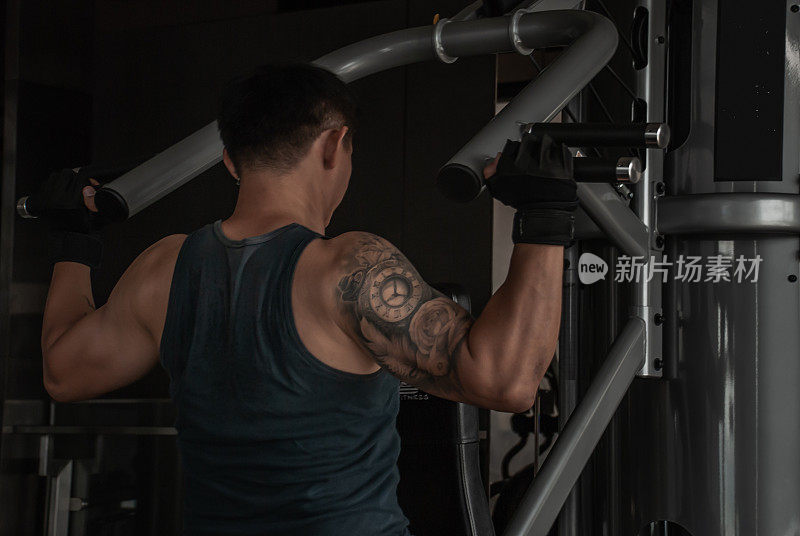 在健身房或健身俱乐部，健身者的背部在锻炼机上举重。