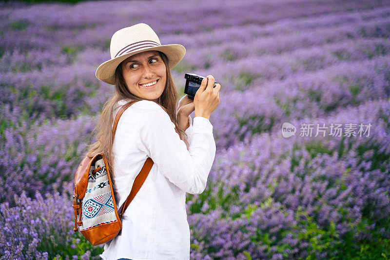 年轻的女游客在盛开的薰衣草地里拍照。旅游热。