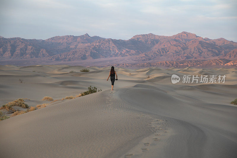 年轻的南亚妇女行走在死亡谷的沙丘上-坚强的独立旅行背景