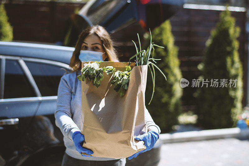 买菜回家的女人。戴上防护口罩和手套