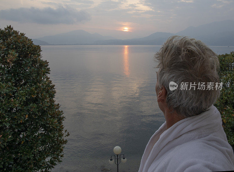 透过阳台门看日出时穿浴袍的男人