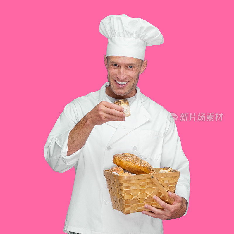 白人年轻男性面包师面前有色背景穿着裤子，拿着面包